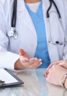 Close up of a doctor and  patient hands discussing something while sitting at the table . Medicine and health care concept